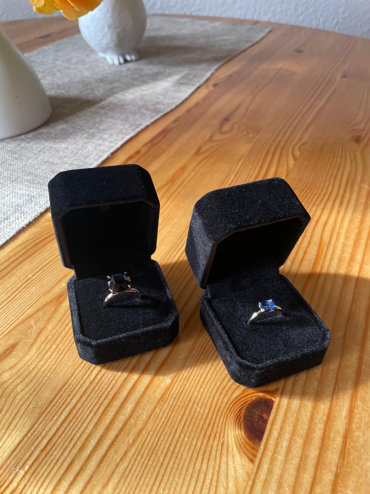 Two finished gemstone rings displayed in black presentation boxes.