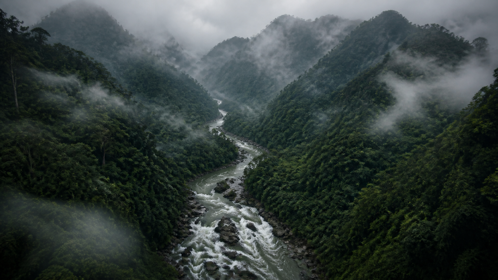 Misty jungle mountains and a fast river cutting through Northern Thailand.